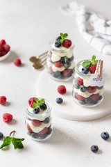 Berry yogurt with fresh strawberries and blueberries in jars. Healthy breakfast parfait in glass jars. Close up. Summer dessert