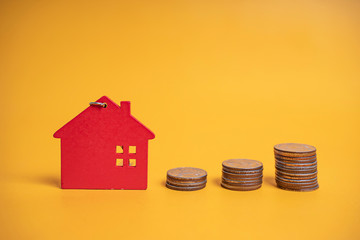 concept mock up value added tax of toy miniature house and coins, representing real estate, income, expenses financial data of added tax money payment on owning property, on isolated yellow background