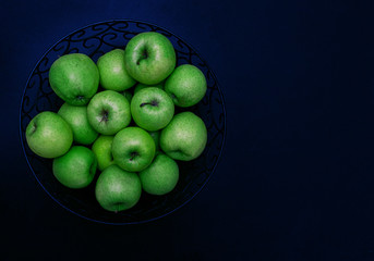 Green apples on a black background. Bright green apples golden delicacy with dark splashes natural color. Left place for text, copy space.