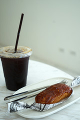 Close up Caramellow eclair (Cream and caramel cake) served with Iced black coffee