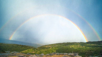 Fototapeta na wymiar Rainbow on green hills; beautiful natural landscape
