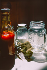 Barattolo, bicchieri e dollari sul tavolo