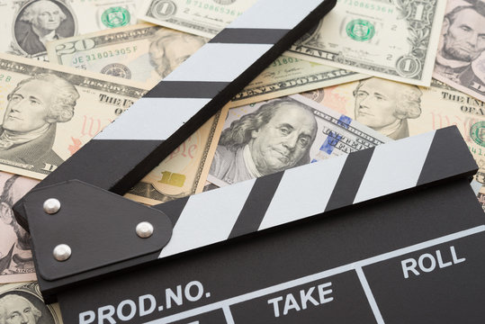 Cinema clapperboard on US dollars banknote bill background - Movie entertainment industry to make money concept