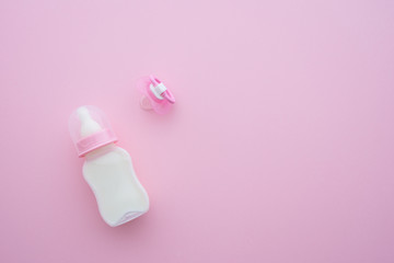 Pacifier or soother, baby toddler feeding plastic bottle and soft teat with milk on pink background with copy space. Newborn accessories prepare for baby girl or toddler from day one, breastfeeding