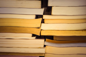 Stack of many old books on shelf in book store or library room with white wall background, vintage tone. Knowledge learning, education, bachelor degree in university or back to school concept.