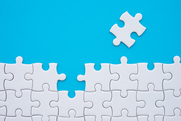 The last piece of jigsaw puzzle to complete task on blue background. Business strategy teamwork, problem solving concept. Teamwork is collaborative effort of team to achieve goal or complete mission.