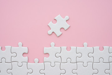 The last piece of jigsaw puzzle to complete task on pink background. Business strategy teamwork,...