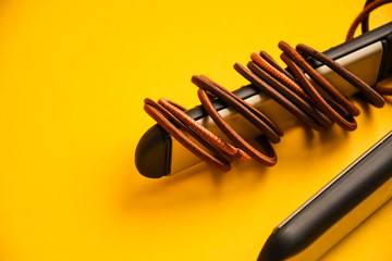 scrunchy with Modern Curling iron and hair iron for straightening on yellow background with copy...