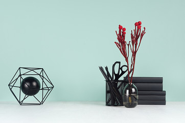 Light spring school workplace with black stationery, books, red branch in glass vase, decorative...