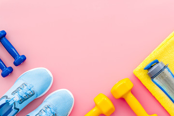 Athletics background with dumbbells, towel, sneakers on pink background top view copy space