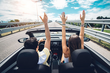 Enjoy travel. Couple in love with arms outstretched enjoy driving on a cabriolet car on the road at vacation. 
