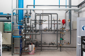 Heating system's cooper pipes with ball valves and manometer on a grey wall