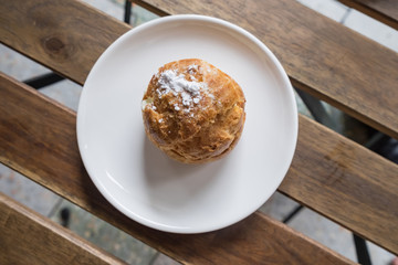 Sweet brown cream choux with icing on a wood background.