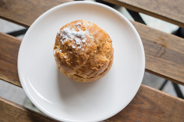 Sweet brown cream choux with icing on a wood background.