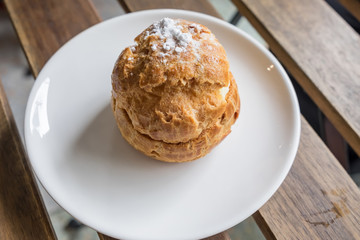 Sweet brown cream choux with icing on a wood background.