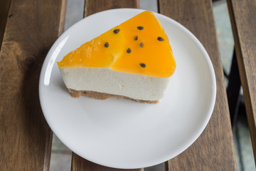 Fresh fruit cake decorated with passionfruit and oranges mousse on wood background. Modern