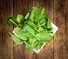 Portion of fresh Spinach on a wooden table (close-up shot)