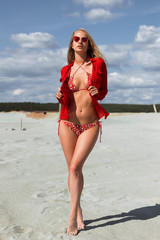 Trendy woman in bright swimwear touching hair at seaside