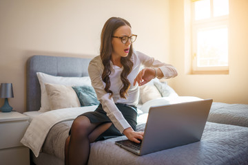 Fototapeta premium Businesswoman on business trip sitting in hotel room and working on laptop.