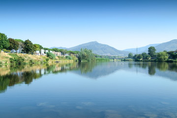 Beautiful natural lakescape under blue sky. Mountains and trees reflecting on the water