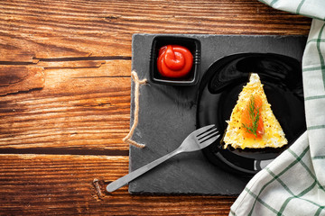 piece omelet black plate with ketchup. copy space.