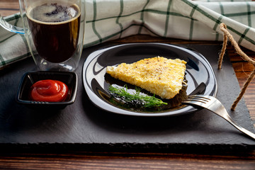 piece of omelet on black plate with ketchup.