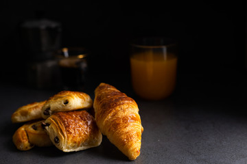 Breakfast table with croissants and cinnamon buns with fresh orange juice.