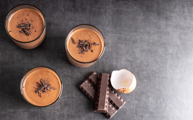 Homemade chocolate mousse made of dark chocolate,eggs, fresh cream and sugar on a wooden table. Top view.