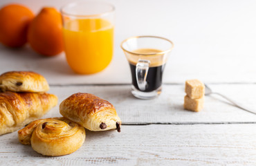 Breakfast table with croissants and cinnamon buns with fresh orange juice.