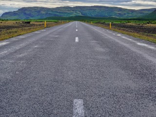 direct road goes to green hills, cloudy summer day, nature of Iceland