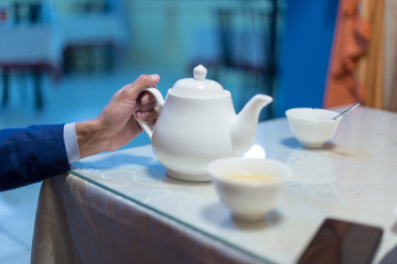 Business man pours tea in a cafe or restaurant