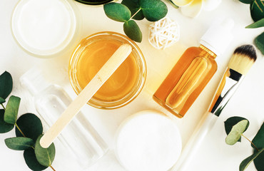 Cosmetic jars of golden honey for making natural skincare cosmetics, face and body beauty therapy, eucalyptus leaves, top view. Home spa treatment. 