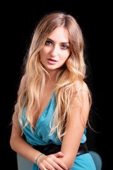Naklejka premium ritratto ragazza bionda sexy con occhi azzurri su sfondo nero, posa di una donna bionda con occhi azzurri italiana in primo piano che posa con atteggiamento sexy su sfondo nero e truccata