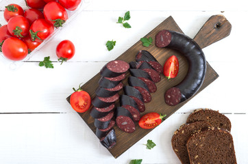 Morsilla - blood sausage. Pieces of Spanish black pudding on a wooden cutting board on white...