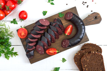 Morsilla - blood sausage. Pieces of Spanish black pudding on a wooden cutting board on white...