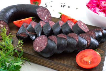 Morsilla - blood sausage. Pieces of Spanish black pudding on a wooden cutting board on white...