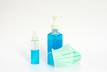 Medical alcohol gel in hand pump bottle and cleaning alcohol in handy spray bottle with surgical mask shot on white background.