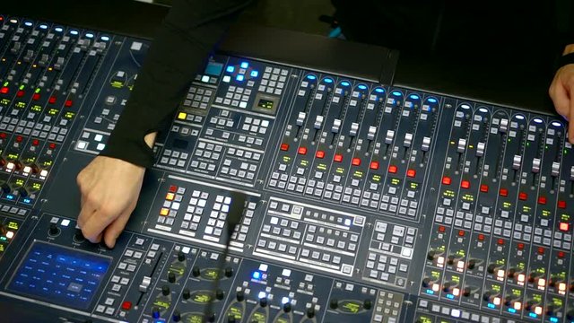sound producer is working on audio mixing console in recording studio, closeup