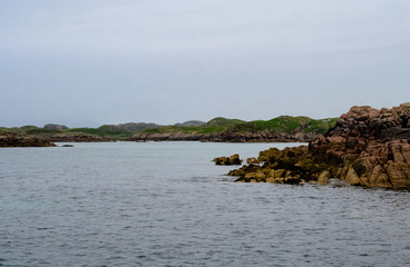 Textured volcanic rocks emerging from the water surface in the northern sea of Scotland. Shot taken from the ferry boat from Mull island and The little and wild Staffa island