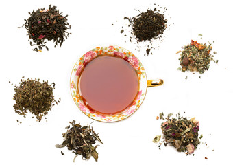 Assortment of dry tea leaves and cup of tea in the centre