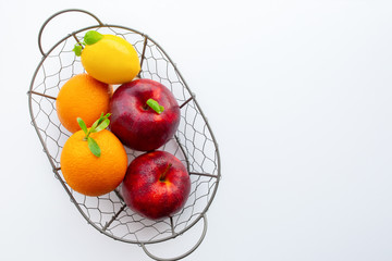  A basket of fruits. A set of vitamins. A metal basket with apples and oranges. Vitamin C. Lemon. Vegetarian, vegan food. Proper nutrition. Carbohydrates. A healthy set. Citrus fruits.apples.