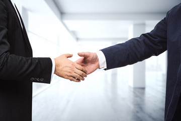 Two businessmen shake hands on the background of empty modern office, signing of a contract...