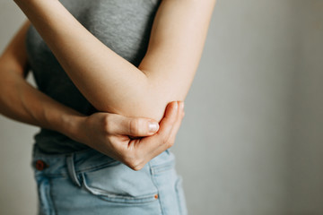 Elbow injury and fatigue at work. Damage zone, image on an empty background. Spasm on the girl's arm.