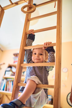 two year old child climbs stairs on gymnastic complex at home