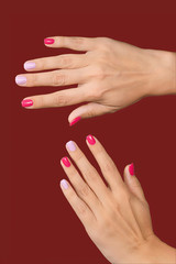 Closeup view vertical photography of two beutiful manicured female hands isolated on dark background. Nails painted in trendy asymmetric two colours naildesign.