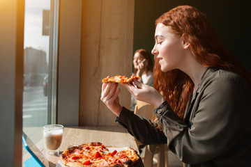 Female model holds a piece of pizza in her hands. Young woman eating pizza