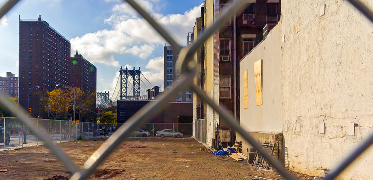 Vacant lot and Manhattan Bridge behind wire mesh in Manhattan in New York, USA