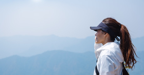 A woman hiking and standing on the top of mountains looking at a beautiful view