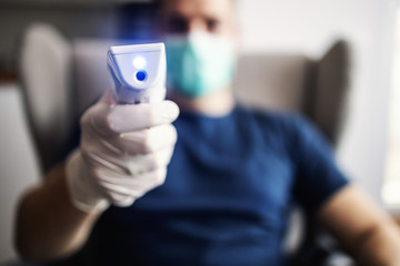 Young man measuring temperature, world pandemic, stay at home.