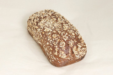 Gray loaf of rye bread sprinkled with nuts, an assortment of bread and bakery products. Closeup on a light background